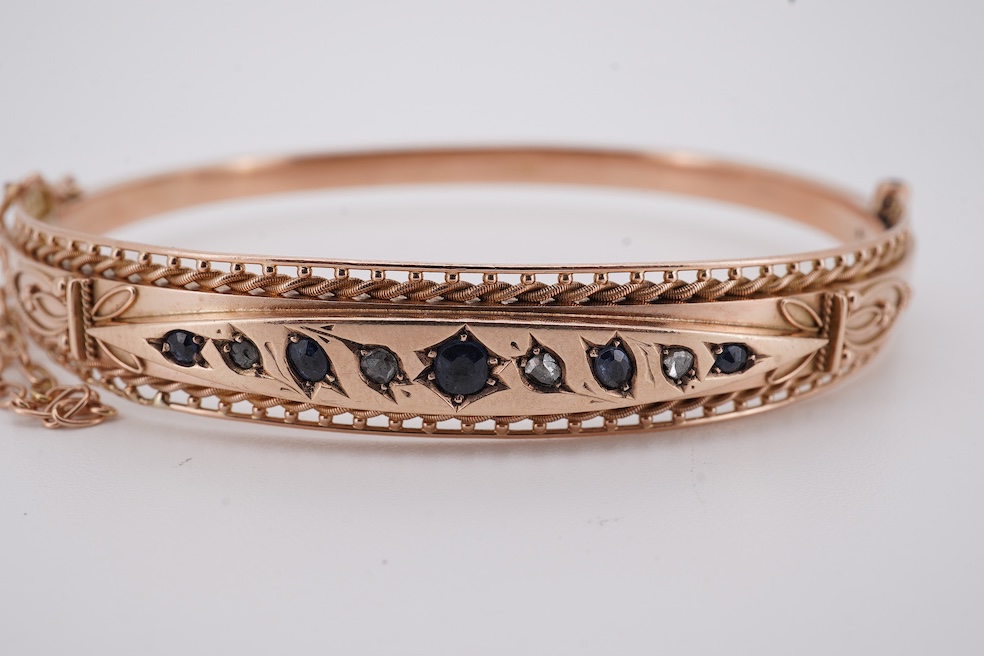An Edwardian 9ct gold, sapphire and diamond set hinged bangle, Chester, 1909, interior diameter 57mm, gross weight 10 grams. Condition - poor